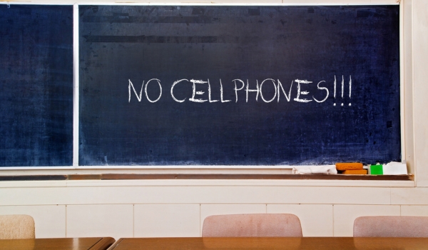 Very old scratched school board with "No Cell phones" written on it with chalk
